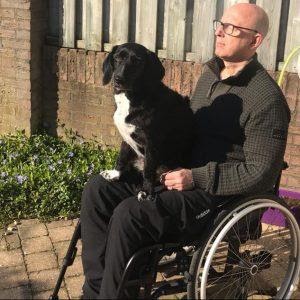 Edwin Donders in rolstoel, met hond op schoot